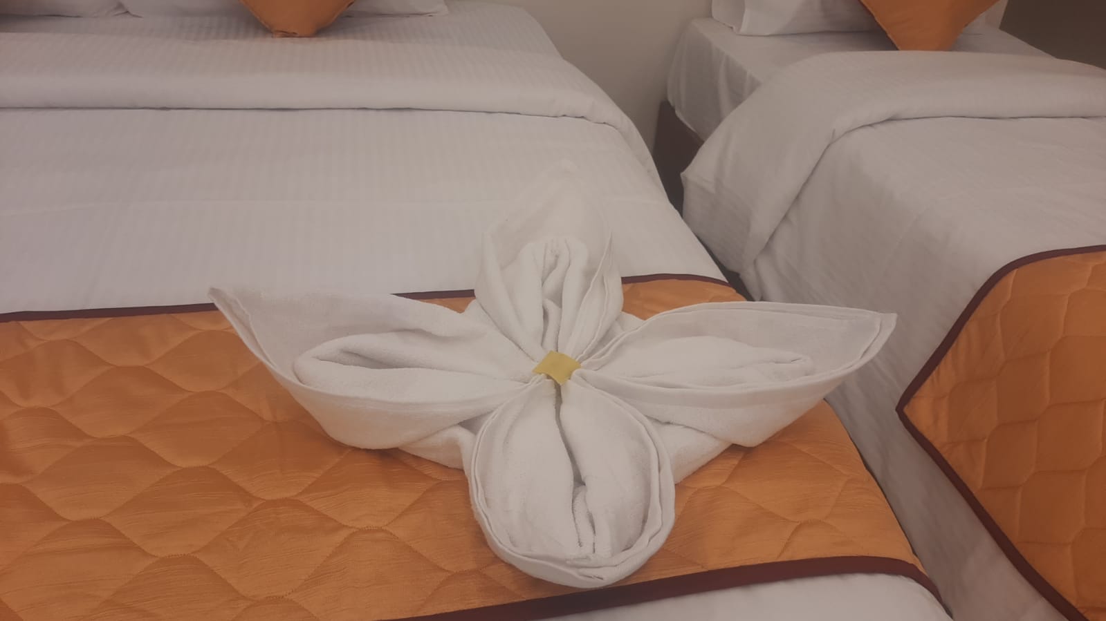 Decorative towel arrangement on an orange bed runner